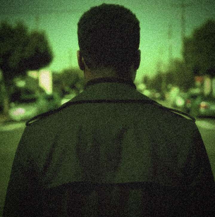 K.R.W.N. from behind, walking into a city street at dusk
